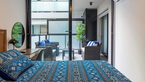Een moderne hotelkamer met een groot bed, een balkon met zitplaatsen en uitzicht op de stad.