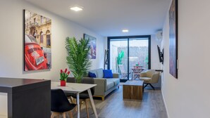 Een moderne woonkamer met een bank, salontafel en een eethoek met stoelen. Een groot raam biedt uitzicht op het omliggende landschap.