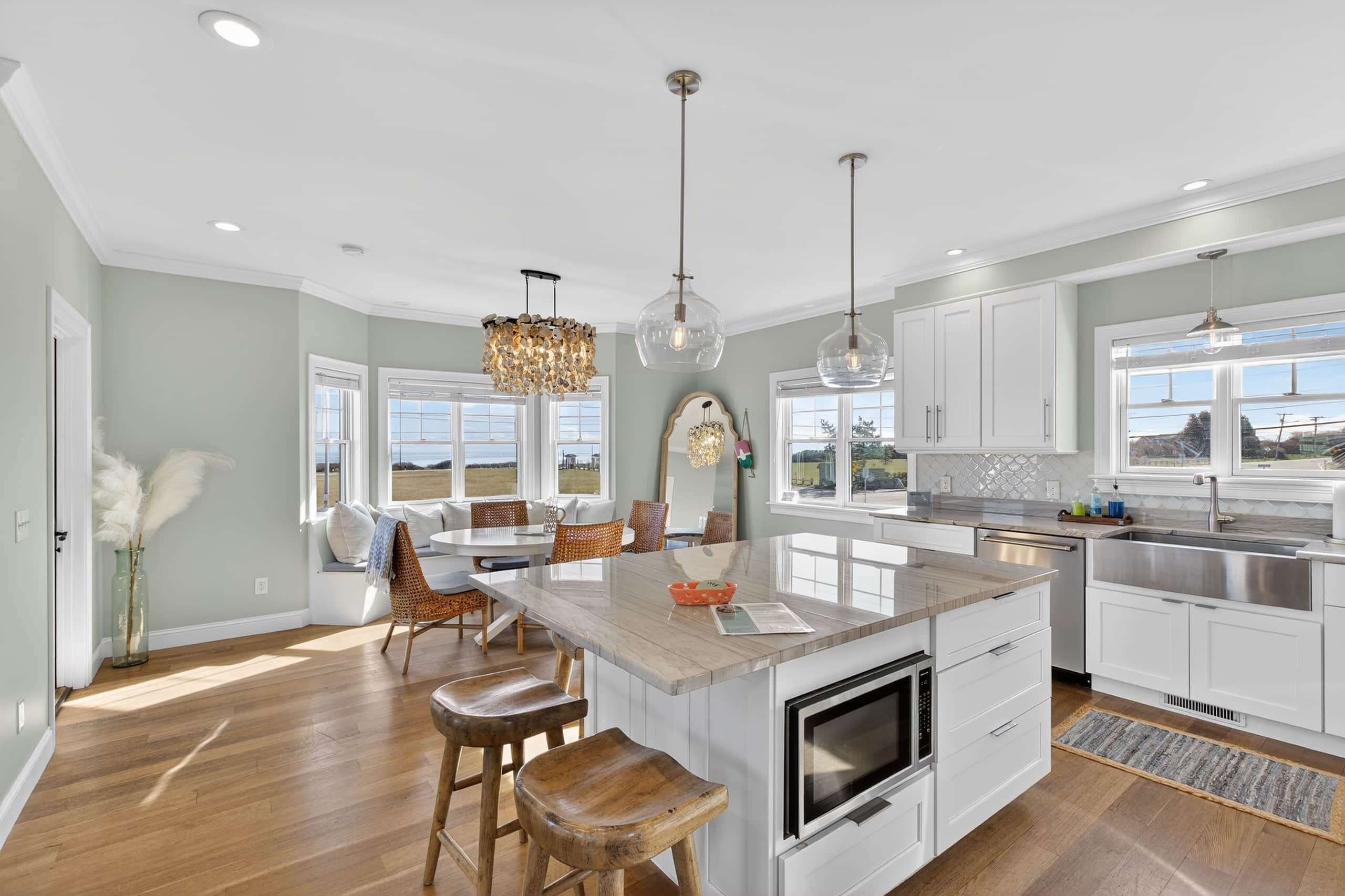 A modern kitchen with a central island, white cabinetry, and pendant lighting.