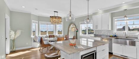 A modern kitchen with a central island, white cabinetry, and pendant lighting.