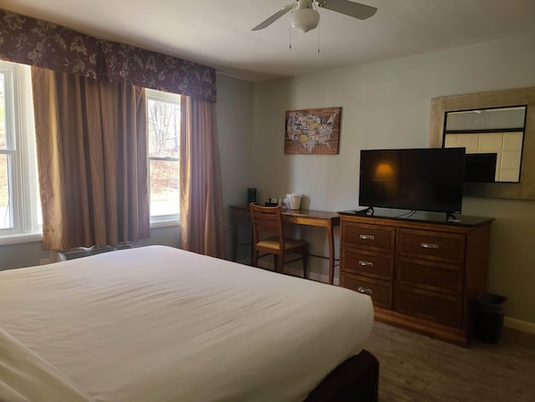 A hotel room with a large bed, a desk with a chair, a television, and a ceiling fan. - Tilton Lodge Inn and Suites (Tilton)