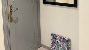 Um banheiro com porta cinza, espelho com moldura preta e um quadro abstrato colorido.