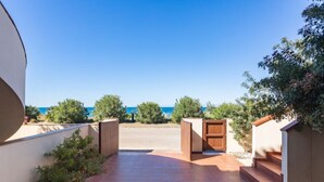 A patio with a view of the sea, a wooden bench, and a small staircase. - Casa del Lentischio (Funtana Meiga)