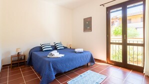 A bedroom with a bed, a nightstand, a window, and a door. - Casa del Lentischio (Funtana Meiga)