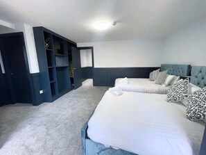 Una habitación de hotel con dos camas, un cabecero azul oscuro y un armario empotrado.