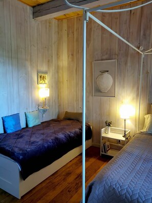 Une chambre avec un lit, une table de chevet, une lampe et une œuvre d’art au mur.