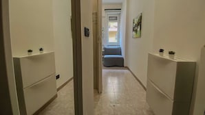 A narrow hallway with white walls and a tiled floor, leading to a room with a bed and a window. - Torino Santa Rita (Turin)