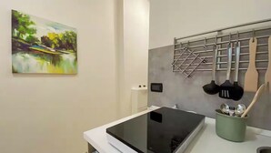 A modern kitchen with a black countertop, a stainless steel rack with utensils, and a painting on the wall. - Torino Santa Rita (Turin)