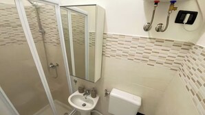 A bathroom with a glass shower enclosure, a sink, a toilet, and a mirror. - Torino Santa Rita (Turin)