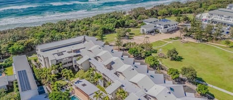 Un resort con varias edificaciones, una piscina y vista al océano.