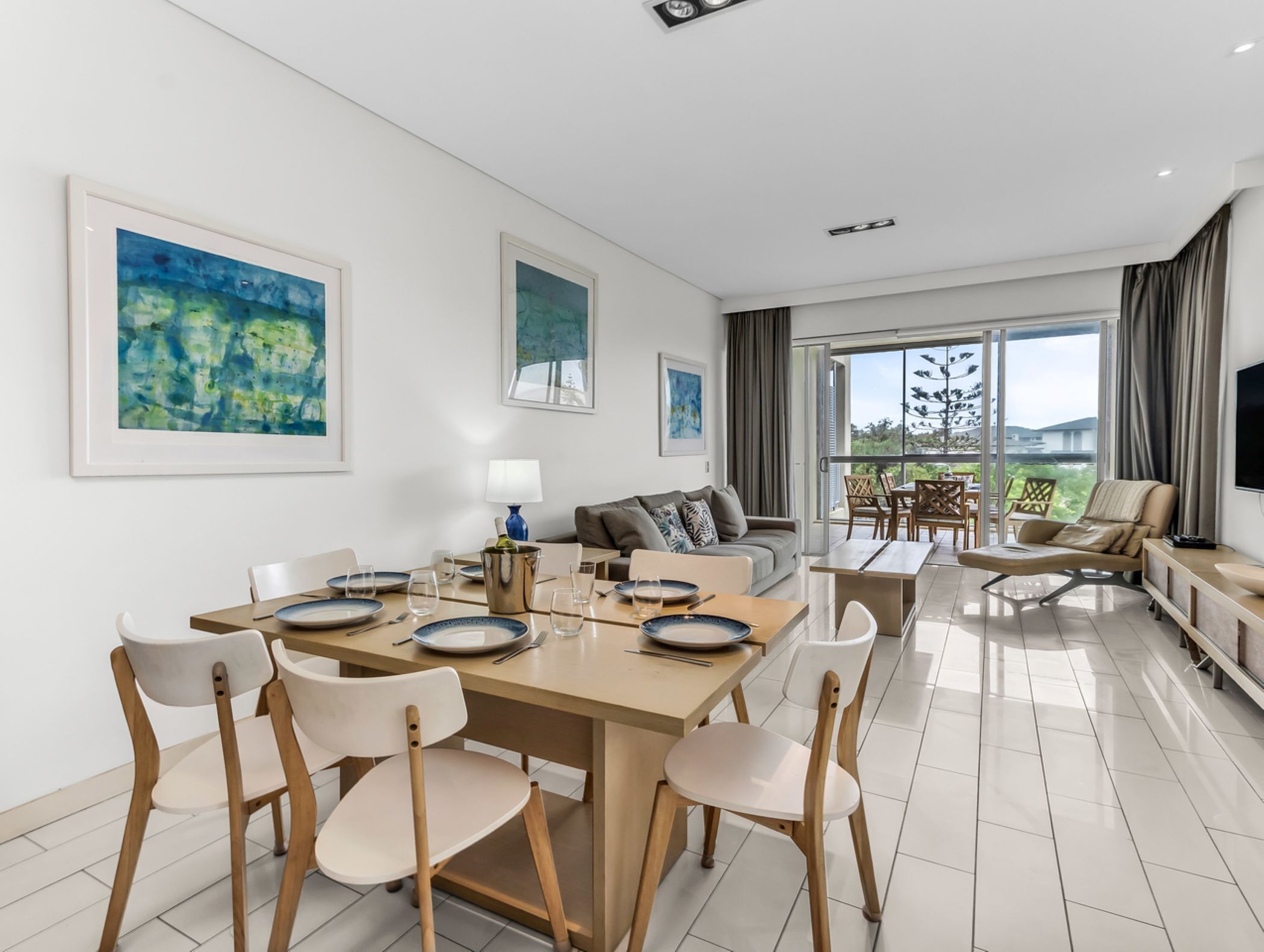 A modern dining area with a wooden table, white chairs, and a blue lamp.