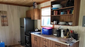 Una cocina compacta con gabinetes de madera, estufa empotrada y refrigerador.