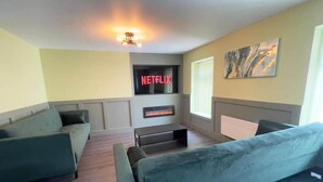 Un soggiorno con camino, il logo Netflix e un quadro appeso al muro.