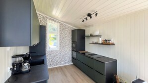 A modern kitchen with dark cabinetry, a built-in stove, and a coffee maker. - 2 bedroom amazing home in Mandal (Mandal)