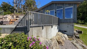 A wooden cabin with a metal railing, large windows, and a stone pathway leading to it. - 2 bedroom amazing home in Mandal (Mandal)