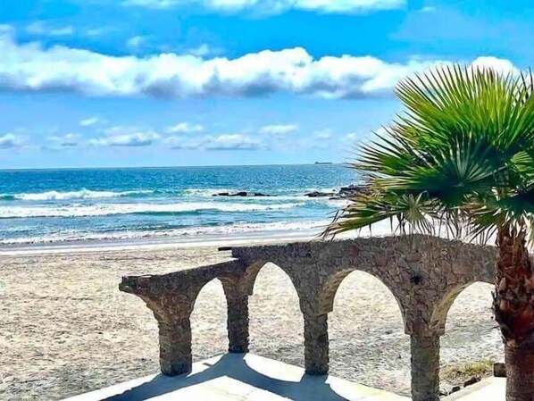 Une plage avec une arche en pierre et un palmier.