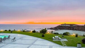 Une propriété située sur la côte, dotée d’une piscine, d’un espace extérieur aménagé et offrant une vue sur l’océan au coucher du soleil.