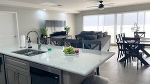 Une cuisine moderne dotée d’un grand îlot central, d’appareils électroménagers intégrés et d’un coin repas avec une table et des chaises.