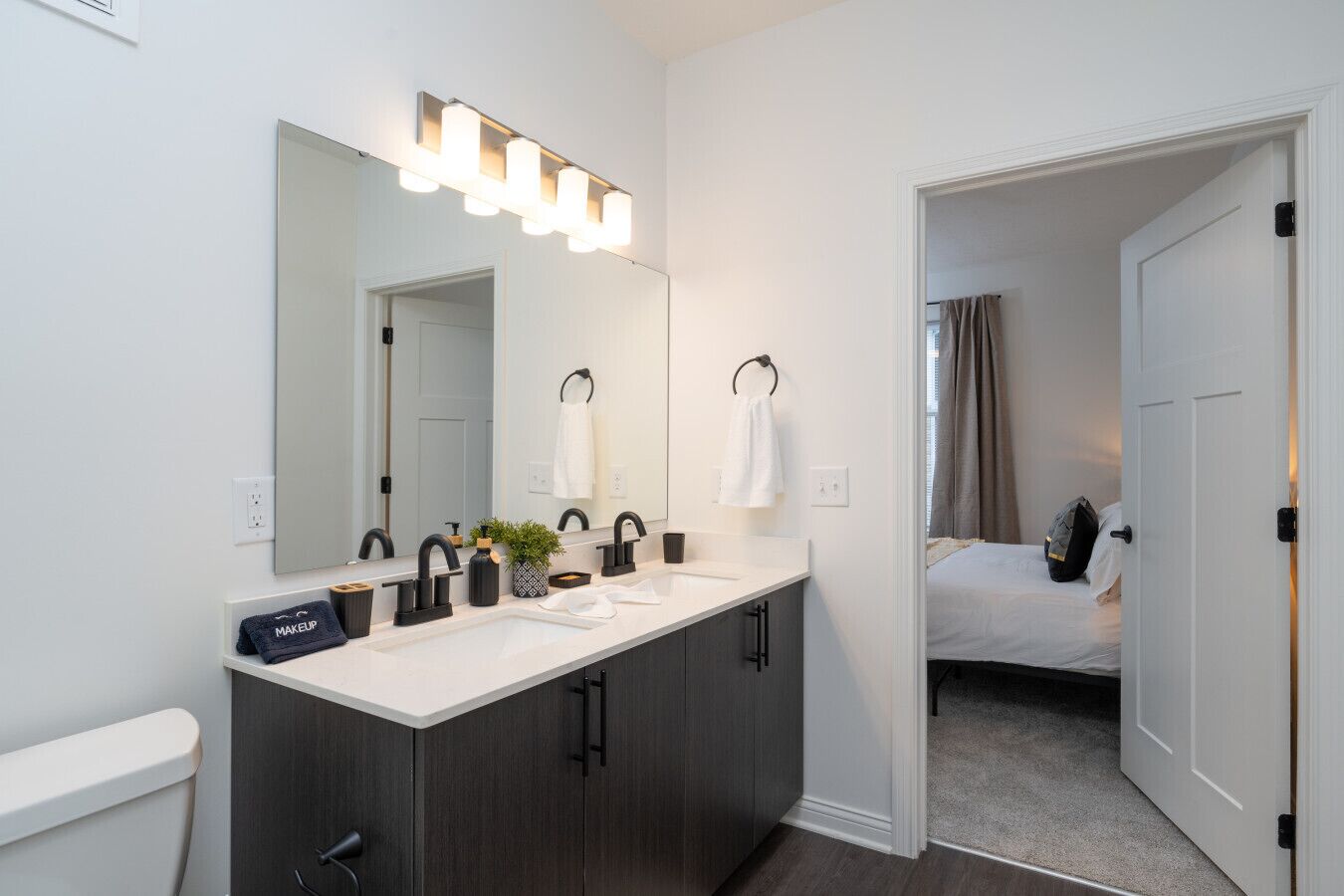 A modern bathroom with a double sink vanity, a large mirror, and a walk-in shower.