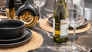 Un comedor moderno con una mesa de mármol, una botella de vino y copas.