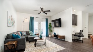 Ein modernes Wohnzimmer mit einem grauen Sofa, einem Couchtisch und einem an der Wand montierten Fernseher.