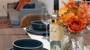 Una mesa de comedor dispuesta con cuencos y platos azules, una botella de vino y un florero con flores.