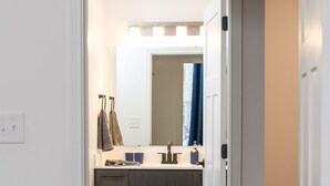 Un baño moderno con tocador, espejo y perchero.