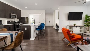 Una cocina moderna con armarios oscuros, una isla central y un comedor con mesa y sillas.