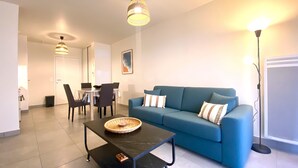 A modern living room with a blue sofa, a dining table with chairs, and a coffee table. - Remember - T2 near the ocean (Mimizan)