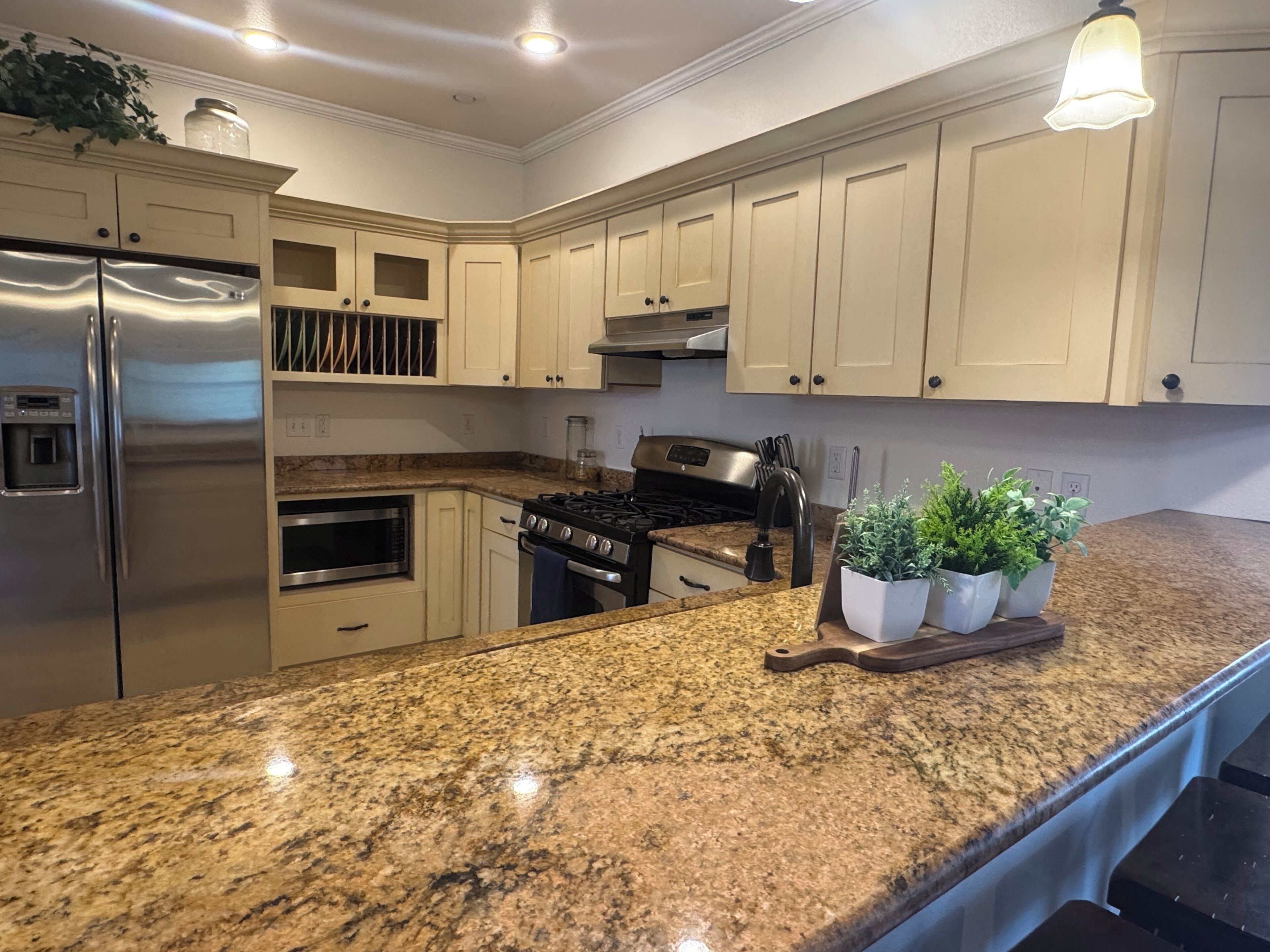 Una cocina con encimeras de granito, electrodomésticos de acero inoxidable y armarios de tonos claros.