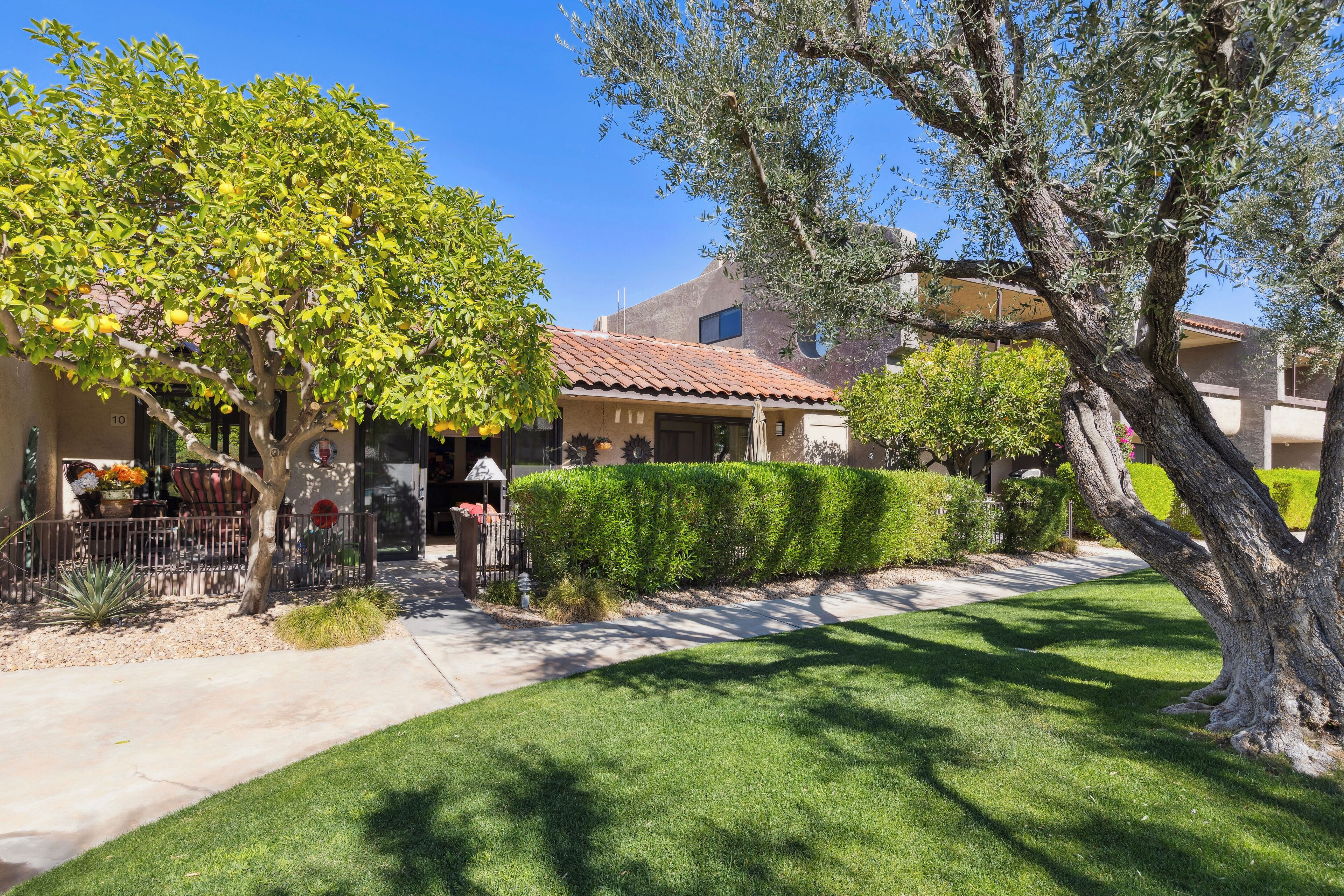 A residential property with a well-maintained lawn, mature trees, and a patio area.