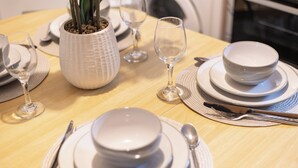 A dining table set with white plates, bowls, and cutlery, including a potted plant. - Rochester Retreat - Charming 3 Bedroom House (Rochester)