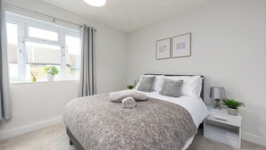 A bedroom with a bed, bedside tables, a window with curtains, and two framed pictures on the wall. - Rochester Retreat - Charming 3 Bedroom House (Rochester)