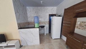 A modern kitchen with marble walls, a built-in fridge, a water dispenser, and wooden cabinets.