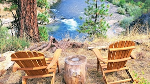 Two wooden Adirondack chairs facing a river with a forest backdrop. - Private Hot Spring, Perfect for Couples, No Shared Spaces, 1 Hour North of Boise (Garden Valley)