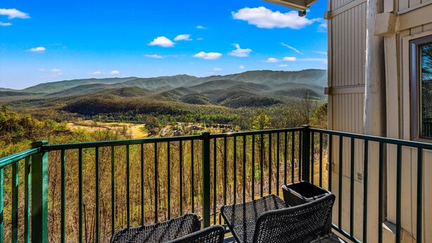 A balcony with wicker chairs overlooking a mountainous landscape. - 🔥 Mountain Escape | Fireplace, Sky Deck & Year-Round Resort Perks! (Gatlinburg)