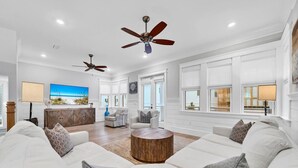 A spacious living room with a large white sofa, a wooden coffee table, and two ceiling fans. - Golf Cart, Bikes, The Big Chill, Shuttle to Beach Seasonally, 2 Pools! (Alys Beach)