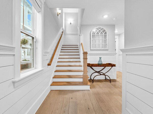 A staircase with wooden steps and a wooden handrail, leading to a landing with a table and a vase. - Golf Cart, Bikes, The Big Chill, Shuttle to Beach Seasonally, 2 Pools! (Alys Beach)