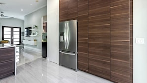 A modern kitchen with a stainless steel refrigerator, wooden cabinetry, and a clean, minimalist design.
