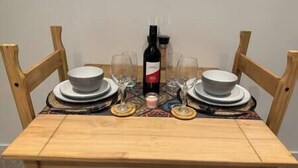 Une table de salle à manger en bois, mise avec des assiettes, des verres et une bouteille de vin.