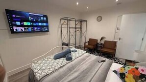 Une chambre d’hôtel comprenant un lit, un téléviseur fixé au mur, une chaise et une armoire.
