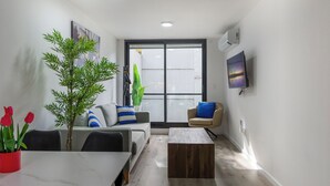 Una sala moderna con un sofá, una mesa de centro y una planta en maceta.