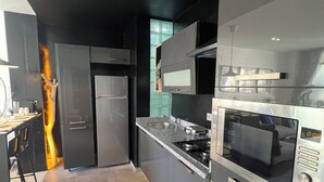 A modern kitchen with a black and grey color scheme, stainless steel appliances, and a tiled floor. - Stay in GAUTHIER studio M (Casablanca)