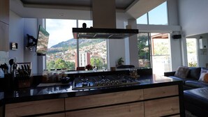 A modern kitchen with a central island, large windows, and a view of a cityscape. - Exclusive Luxury In Heart of Medellin. (Medellín)