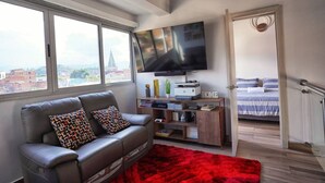 A modern living room with a leather sofa, a red rug, a flat-screen TV, and a bookshelf. - Exclusive Luxury In Heart of Medellin. (Medellín)