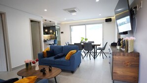Un saló modern amb un sofà blau, una taula de cafè i zona de menjador amb cadires i taula.