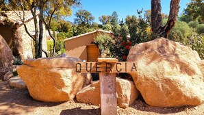 Une construction rustique en pierre, agrémentée d’une enseigne en bois sur laquelle on peut lire « QUERCIA ».