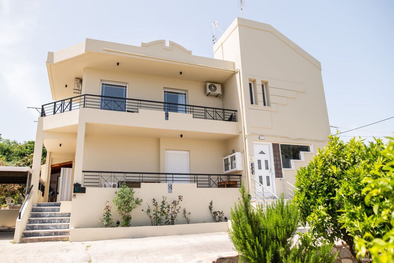 A two-story building with a balcony, a staircase, and a small garden area.