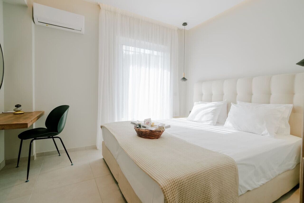 Quarto de hotel com uma cama, uma escrivaninha e uma cadeira.