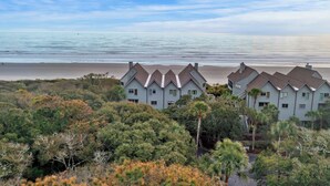 A beachfront property with multiple buildings, a sandy beach, and dense vegetation.